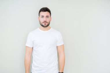 Üzerinde rahat beyaz t-shirt giyen genç yakışıklı adam arka plan gevşek yüzünde ciddi bir ifade ile izole. Basit ve doğal kameraya bakıyor.