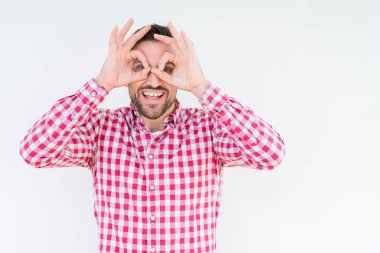 Dilini, parmaklarının arasından baktığını yapışmasını dürbün gibi ok jest yapıyor izole arka plan üzerinde gömlek giymiş yakışıklı delikanlı. Deli ifade.