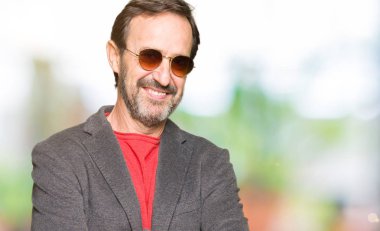 Orta yaş yakışıklı iş adamı ile gülümseyen güneş gözlüğü mutlu yüz giyen silah kameraya bakarak geçti. Olumlu bir kişi.