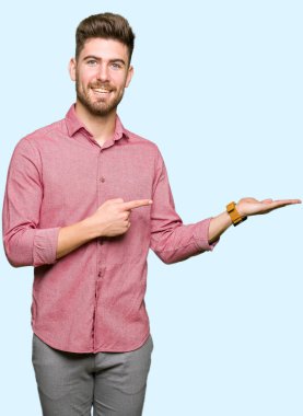 Hayret ve el ile sunulması ve parmak ile işaret ederken kameraya gülümseyen genç yakışıklı iş casual adam.