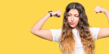 Casual beyaz t-shirt gösteren giyen genç güzel kadın gururlu gülümseyen kas silah. Fitness kavramı.