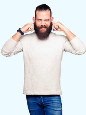 Yüksek sesle müzik gürültü rahatsız ifade parmaklarıyla kulaklarıyla kapsayan geçici kazak giyen genç sarışın adam. Sağır kavramı.