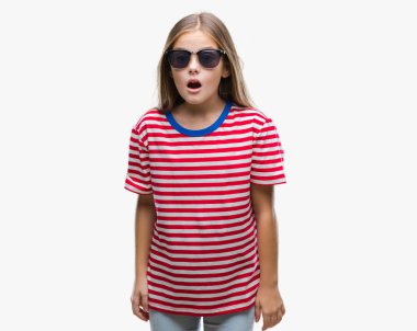 Genç güzel kız korkuyor ve şok sürpriz ifade, korku ve heyecan yüz ile izole arka plan üzerinde güneş gözlüğü takıyor.