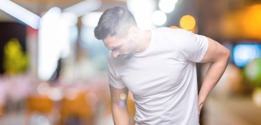 Gece boyunca açık havada beyaz t-shirt giyen yakışıklı adam arka plan geri el ile kas ağrısı dokunmadan acı sırt ağrısı,