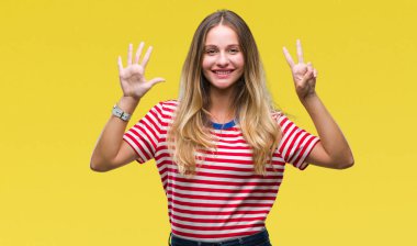 Genç güzel sarışın kadın gösterilen ve parmakları ile işaret izole arka plan yüzünden kendinden emin ve mutlu gülümseyerek süre yedi numara.