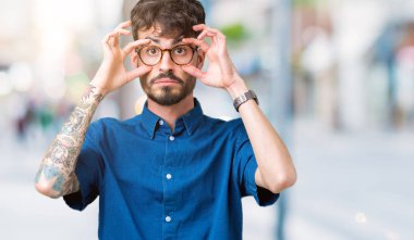 Parmaklarıyla, Uykulu ve sabah yorgunluk için yorgun gözlerini açmaya çalışırken izole arka plan üzerinde gözlük takan genç yakışıklı adam