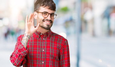 Bir işitme söylenti ya da dedikodu için dinleme kulak üzerinde el ile gülümseyen izole arka plan üzerinde gözlük takan yakışıklı delikanlı. Sağırlık kavramı.