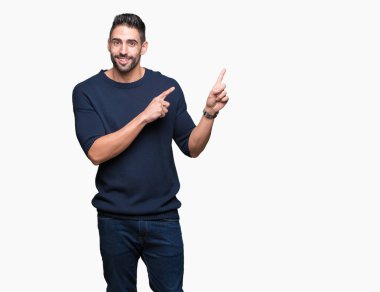 Gülümseyen ve iki elleri ve parmakları ile tarafına işaret kamera bakarak izole arka plan üzerinde kazak giyen genç yakışıklı adam.