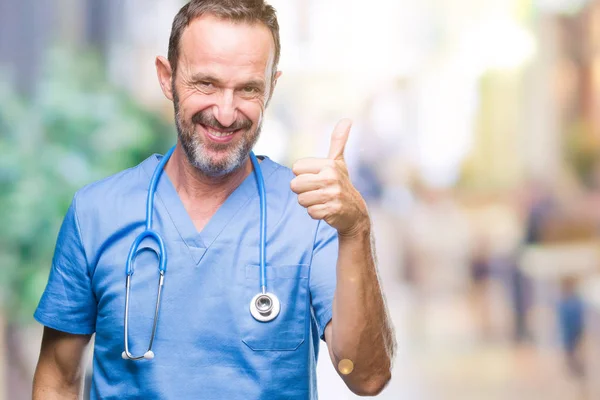 中年白发高级医生在孤立的背景下穿着医疗制服 用手做着快乐的大拇指动作 通过显示成功来批准镜头的表达 — 图库照片