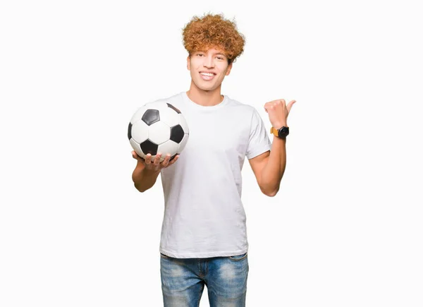 Joven Hombre Guapo Sosteniendo Pelota Fútbol Apuntando Mostrando Con Pulgar — Foto de Stock