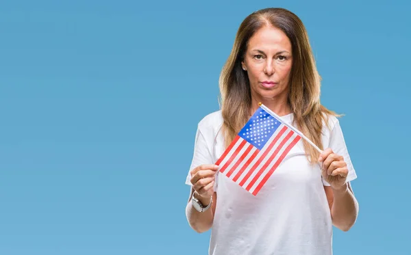 Middle age hispanic woman holding flag of United States of America over isolated background with a confident expression on smart face thinking serious