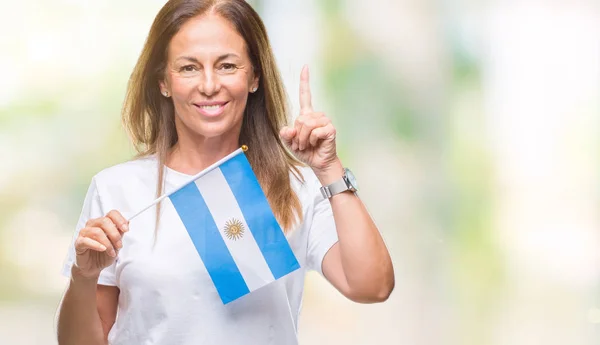 幸せそうな顔 ナンバーワンのアイデアや質問ポインティング指で孤立した背景にアルゼンチンの旗を保持している中年ヒスパニック女性を驚かせた — ストック写真