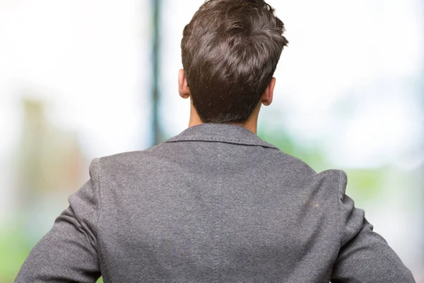 Young business man wearing glasses over isolated background standing backwards looking away with arms on body