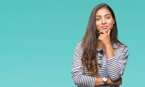 Young beautiful arab woman wearing sunglasses over isolated background looking confident at the camera with smile with crossed arms and hand raised on chin. Thinking positive.