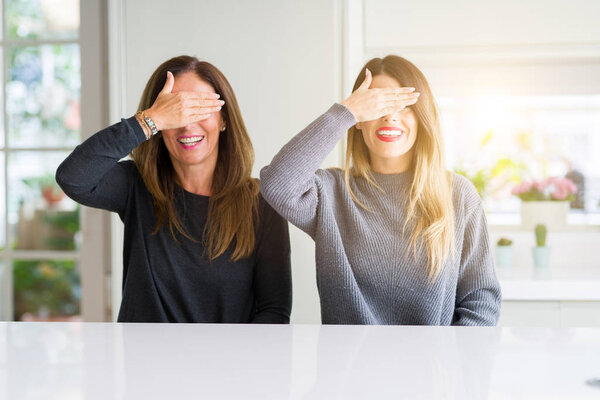 Семья матери и дочери вместе дома улыбается и смеется, закрывая глаза от удивления. Слепая концепция
.
