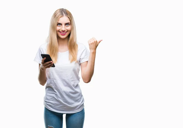 年轻漂亮的金发女人使用智能手机在孤立的背景下指向和显示与拇指向上微笑的一面与快乐的脸 — 图库照片