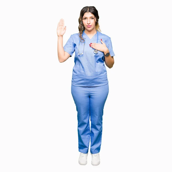 忠誠の宣誓を行う医療の制服 Swearing 胸と開いた手のひらで手を着ている若い大人医師女性 — ストック写真