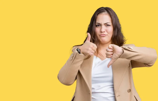 Beautiful plus size young woman wearing winter coat over isolated background Doing thumbs up and down, disagreement and agreement expression. Crazy conflict