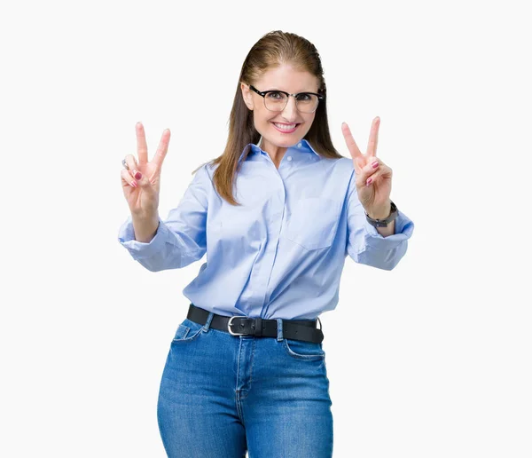 美しい中年成熟したビジネスの女性勝利のサインをやって指を表示するカメラを笑みを浮かべて隔離された背景にメガネを着用します — ストック写真