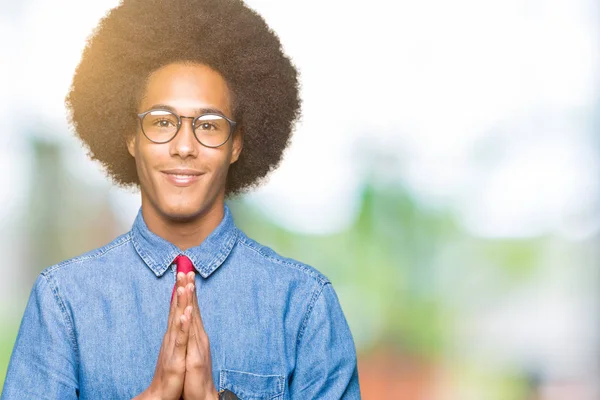 非洲青年商人与非洲头发戴眼镜和红色领带祈祷双手在一起请求原谅微笑自信 — 图库照片