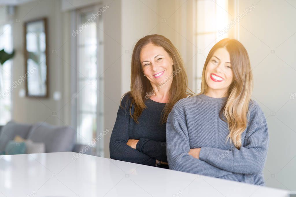 Beautiful family of mother and daughter together at home happy face smiling with crossed arms looking at the camera. Positive person.