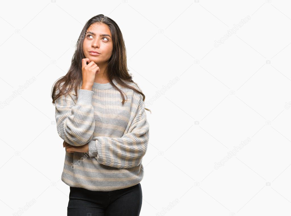 Young beautiful arab woman wearing winter sweater over isolated background with hand on chin thinking about question, pensive expression. Smiling with thoughtful face. Doubt concept.