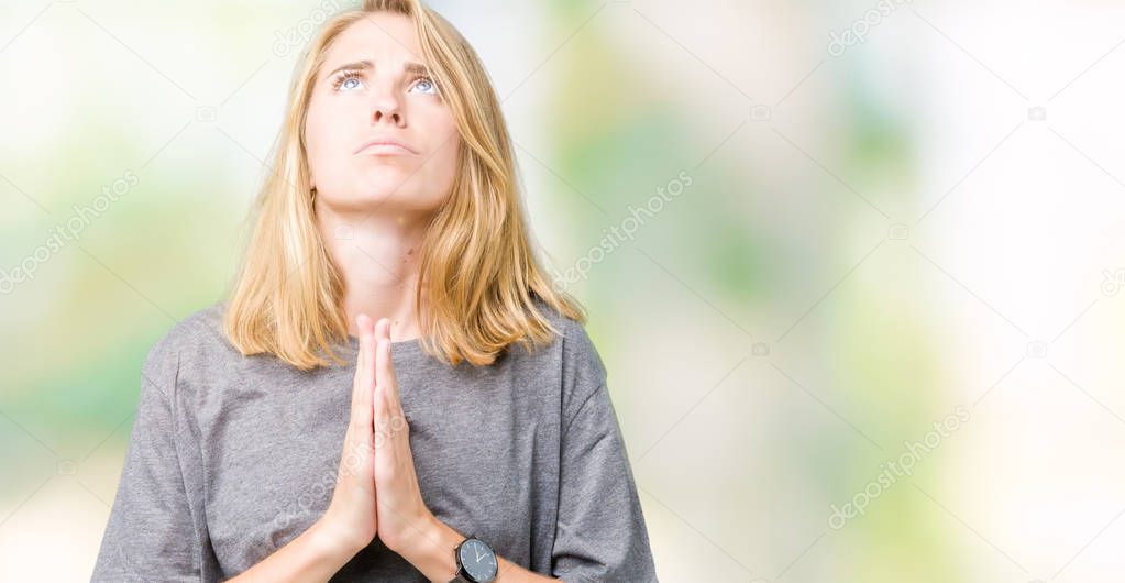 Beautiful young woman wearing oversize casual t-shirt over isolated background begging and praying with hands together with hope expression on face very emotional and worried. Asking for forgiveness. Religion concept.