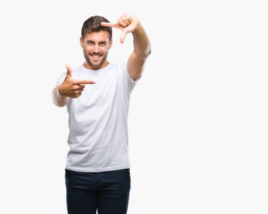 Yakışıklı delikanlı elle yapma çerçeve ve parmakları ile mutlu yüz gülümseyen izole arka plan üzerinde. Yaratıcılık ve Fotoğrafçılık kavramı.