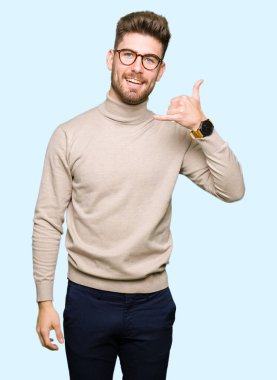 İşin gülümseyen gözlüklü genç yakışıklı iş adamı telefon hareketi ile el ve parmak telefonda konuşuyor gibi. Kavramları iletişim.