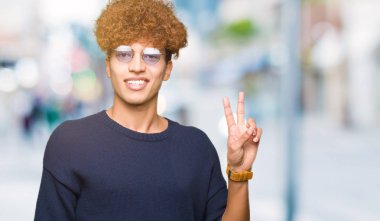 Afro mutlu yüz zafer işareti yaparken kameraya göz kırpıyor ile gülümseyen gözlüklü genç yakışıklı adam. İki numaralı.