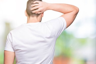Yakışıklı adam açık havada arka plan geriye düşünme hakkında şüphe kafasına el ile üzerine beyaz t-shirt giyen