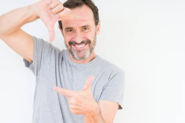 Elle yapma çerçeve ve parmakları ile mutlu yüz gülümseyen izole arka plan üzerinde yakışıklı komuta sizde. Yaratıcılık ve Fotoğrafçılık kavramı.