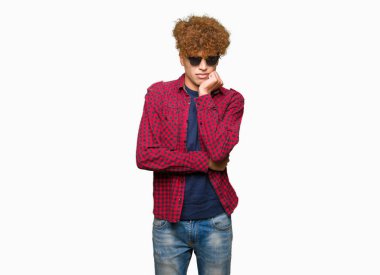 Yakışıklı genç afro saçlı stresli ve gergin elle çivi ısırma ağzına bakarak güneş gözlüğü takıyor. Anksiyete sorunu.