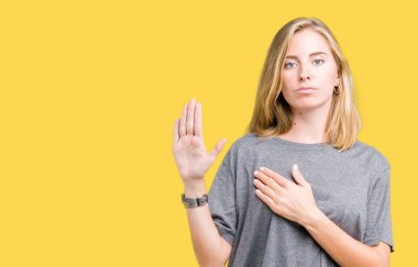 Güzel genç kadın üzerinde büyük boy rahat t-shirt giyen izole arka plan göğüs ve bir sadakat sözü yemin yapma avuç, el ile küfür