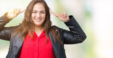 Artı boyutu genç kadın izole arka plan üzerinde bir moda deri ceket giymiş güzel her ikisi ile baş gösteren gülen eller parmak, harika bir fikir ya da düşünce, iyi hafıza