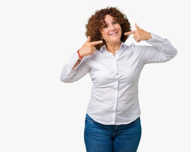 Kendinden emin gösterilen ve işaret parmakları diş ve ağız ile gülümseyen izole arka plan güzel orta ager üst düzey businees kadın. Sağlık kavramı.