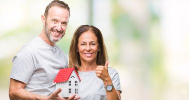 Orta yaş İspanyol rahat çift yeni ev izole arka plan üzerinde mutlu ok işareti yapıyor büyük gülümseme ile satın parmaklarıyla, mükemmel işaret parmak