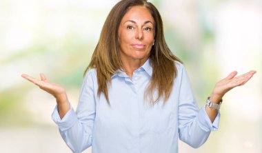 Güzel orta yaş iş izole arka plan clueless ve şaşkın bir ifadeyle kollar ve eller kaldırdı yetişkin kadın. Şüphe kavramı.