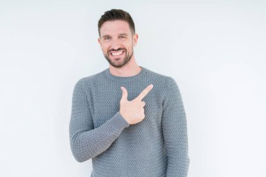 İzole arka neşeli bir gülümseme ile el ve parmak kadar yan yüzünde mutlu ve doğal ifade ile işaret yüz üzerinden rahat kazak giyen genç yakışıklı adam