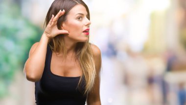 Genç güzel kadın bir işitme söylenti ya da dedikodu için dinleme kulak üzerinde el ile gülümseyen izole arka plan yüzünden. Sağırlık kavramı.