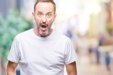 Orta yaş ağarmış komuta sizde korkmuş ve şok sürpriz ifade, korku ve heyecan yüz ile izole arka plan üzerinde beyaz t-shirt giyen.