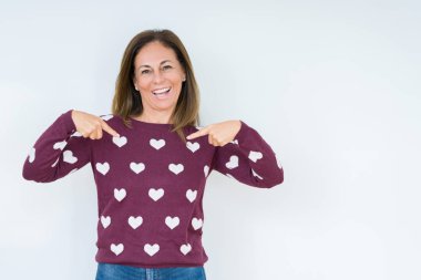 Yüzünde gülümseme ile kendinden emin görünüyorsun, kendini gururlu ve mutlu parmakları ile işaret izole arka plan üzerinde kalp kazak giyen güzel orta yaş kadın.
