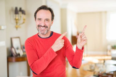 Yakışıklı orta yaş erkek ev gülümseyen ve iki elleri ve parmakları ile tarafına işaret kamera bakıyor.