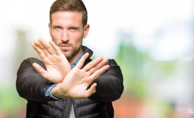 Yakışıklı adam giyen kış bayrak ret ifade geçiş ve avuç içi eksi işareti, kızgın surat yapıyor