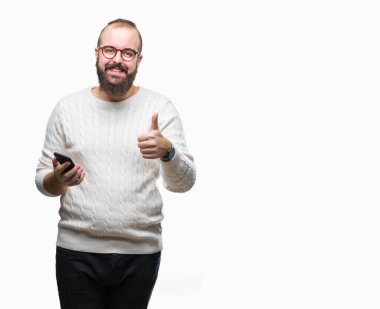 Genç beyaz hipster adam manifatura ok işareti, başparmak ile parmak, mükemmel işareti yapıyor kocaman bir gülümseme ile izole arka plan üzerinde mutlu Smartphone kullanarak ileti gönderme