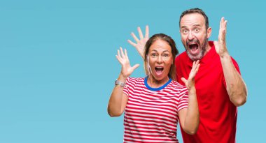 Orta yaş İspanyol çift çılgın kutlama izole arka plan üzerinde seviyorum ve silah ile başarı için yükseltilmiş ve açık gözleri heyecanlı çığlık hayrete düşürdü. Kazanan kavramı