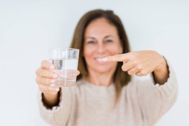 Orta yaş kadın bardak su içme arka plan el ve parmak ile işaret çok mutlu izole