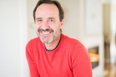 Evde kameraya bakarak gülümseyen yakışıklı orta yaş erkek