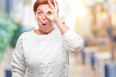 Sürpriz yüz, göz parmaklarının arasından seyir ile ok jest yapıyor izole arka plan üzerinde kış kazak giyen Atrractive üst düzey beyaz Kızıl saçlı kadın şok. İmansız ifade.