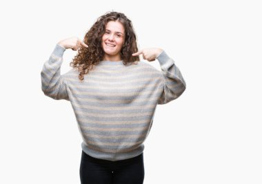 Yüzünde gülümseme ile kendinden emin görünüyorsun, kendini gururlu ve mutlu parmakları ile işaret izole arka plan üzerinde kış kazak giyen güzel esmer kıvırcık saçlı Genç kız.